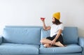 Cropped shot of young smiling woman holding cocktail glass in hand with red alcohol drink sitting on sofa at home Royalty Free Stock Photo