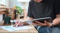 Young stock trader holding digital tablet and analyzing financial graph.