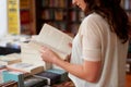 Lost in the pages. A cropped shot of a young woman reading a book while standing in a bookstore. Royalty Free Stock Photo