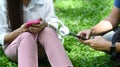 Young woman siting in the park with her boyfriend and using smart phone. Royalty Free Stock Photo