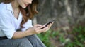 Young woman sitting on bench in the nature park and using smart phone. Royalty Free Stock Photo