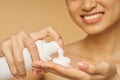 Cropped shot of young woman smiling, holding a bottle of gentle foam facial cleanser isolated over beige background Royalty Free Stock Photo