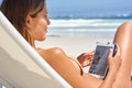 Surfing on the sand. Cropped shot of a young woman using her tablet while relaxing at the beach. Royalty Free Stock Photo