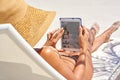 Surfing in the sunshine. Cropped shot of a young woman using her tablet while relaxing at the beach. Royalty Free Stock Photo