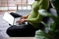 Cropped side view image of a woman using her laptop on a sofa in a living room Royalty Free Stock Photo