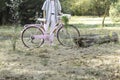 Cropped side view of unrecognizable young fashinable man holding a pink bicycle with a wicker basket and plants Royalty Free Stock Photo