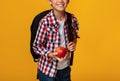 Cropped smart smiling caucasian teenage boy pupil with backpack holding red apple Royalty Free Stock Photo