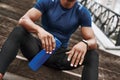 Cropped sportsman is holding water bottle while sitting on steps with outdoors Royalty Free Stock Photo