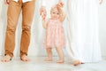 Cropped studio photo of happy, shy, smiling little barefoot baby girl in pink dress and bandelet holding arms together Royalty Free Stock Photo