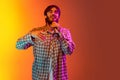 Cropped studio portrait of young boy singing in microphone, posing isolated over gradient yellow red background in neon Royalty Free Stock Photo