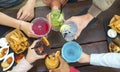 Cropped top view of an unrecognizable group of people in a bar restaurant making a celebratory toast holding colorful cocktails. Royalty Free Stock Photo