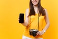 Cropped tourist woman holding mobile smart phone with blank black empty screen isolated on yellow orange background