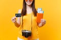 Cropped tourist woman in summer casual clothes holding credit card, passport tickets isolated on yellow orange