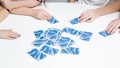Cropped unrecognizable close up children hands holding blue playing cards on white table. Card game for time. Motor game