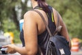 Cropped unrecognizable woman wth summer teeshirt and brown and black leather backpack holds soft drink and cell phone against a bo Royalty Free Stock Photo