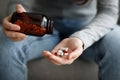 Cropped upset european young lady suffering from depression, grief and loneliness puts a lot of pills in her hand