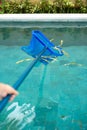 Hands with skimmer net equipment cleaning swimming pool