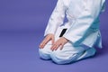 Cropped view of an aikido fighter in a white kimono during the practice of oriental martial arts, over purple background