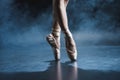 cropped view of ballet dancer in pointe shoes in dark studio