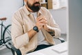 Cropped view of bearded businessman with clenched hands sitting