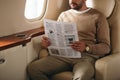 cropped view of bearded man holding newspaper in private jet. Royalty Free Stock Photo