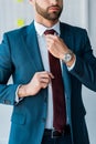 View of bearded recruiter touching tie in office