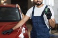 Cropped view of bearded young male inspector measuring paint cover thickness of the car body