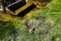 Cropped view of bulldozer bucket at excavation works on grassy sector