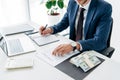 View of businessman holding pen near contract and money in office Royalty Free Stock Photo