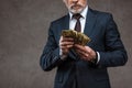 View of businessman in suit holding dollar banknotes in hands on grey Royalty Free Stock Photo