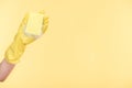 Cropped view of cleaner in yellow rubber glove holding sponge with bubbles on yellow background. Royalty Free Stock Photo