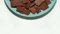 Cropped view of crushed dark chocolate bars stack on a plate isolated over white background