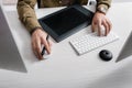 Cropped view of 3d artist using computer mouse and keyboard near graphics tablet