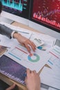 Cropped view of data analysts using charts near calculator and computer monitors