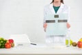 View of dietitian in white coat holding digital scales