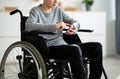 Cropped view of disabled teen boy in wheelchair using smartphone at home, closeup Royalty Free Stock Photo