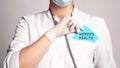 Cropped view of doctor in a white coat and sterile gloves holding a note with text - WOMEN`S HEALTH