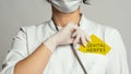 Cropped view of doctor in a white coat and sterile gloves holding a note with words - GENITAL HERPES