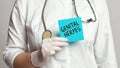 Cropped view of doctor in a white coat and sterile gloves holding a note with words - GENITAL HERPES