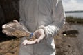 Cropped view of ecologist in protective costume holding bottle