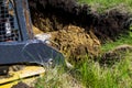 Cropped view of excavator digging foundation pit in grassy field in countryside