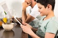 View of father reading newspaper and son using digital tablet during breakfast Royalty Free Stock Photo