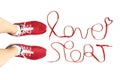 Cropped view of female feet wearing red running sneakers and lettering `love sport` made of athletic shoelaces isolated on white Royalty Free Stock Photo