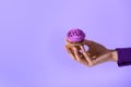 cropped view on female hand holding cupcake with purple glaze, isolated on ultra violet Royalty Free Stock Photo