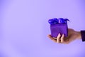 cropped view on female hand holding purple gift, isolated on ultra violet Royalty Free Stock Photo