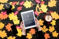 cropped view of female hands with digital tablet with tumblr website on table with autumn leaves coffee and sale