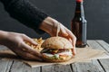 cropped view of female hands with hamburger, french fries and bottle of beer on baking paper Royalty Free Stock Photo