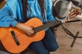 Close-up of a female singer guitarist musician playing guitar while rehearsing new track in the sound recording studio