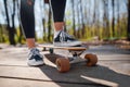 Cropped view of female teenager in casual outfit standing on skateboard Royalty Free Stock Photo