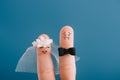 cropped view of fingers as happy bride and nervous groom isolated on blue.